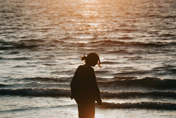 Adult reflecting quietly by the water at dusk, representing trauma and PTSD treatment