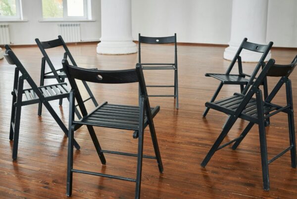Circle of empty chairs in a bright room before a PHP group session