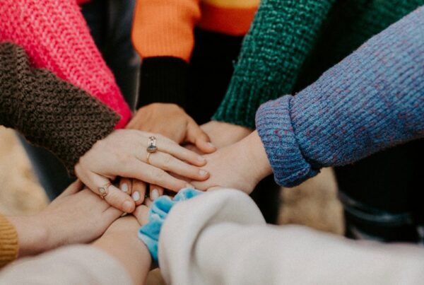 Group of people in sweaters stacking hands, representing a sober support network
