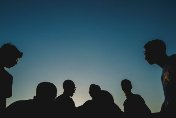 Silhouettes of friends gathered at dusk, representing support through the holidays in recovery