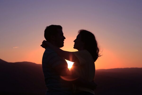 Couple embracing in silhouette at sunset, representing sober dating in early recovery