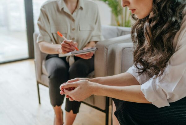 Therapist taking notes while sitting across from a client during an individual therapy session