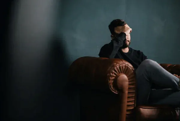 Man sitting alone in a dark room, representing the need for mental health support