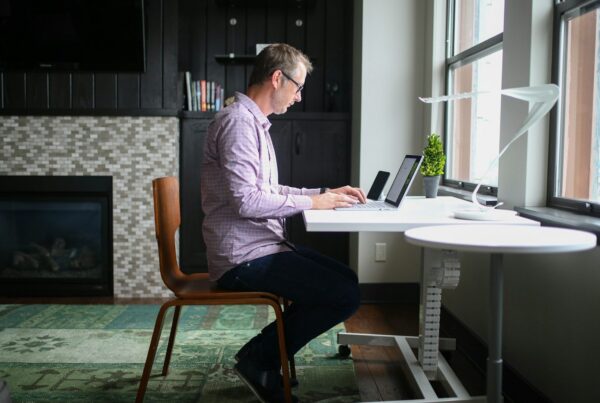 Man working at a desk by a large window, representing adults managing ADHD and addiction