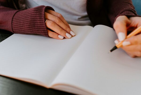 Person writing in an open notebook, like the written work clients complete in Cognitive Processing Therapy