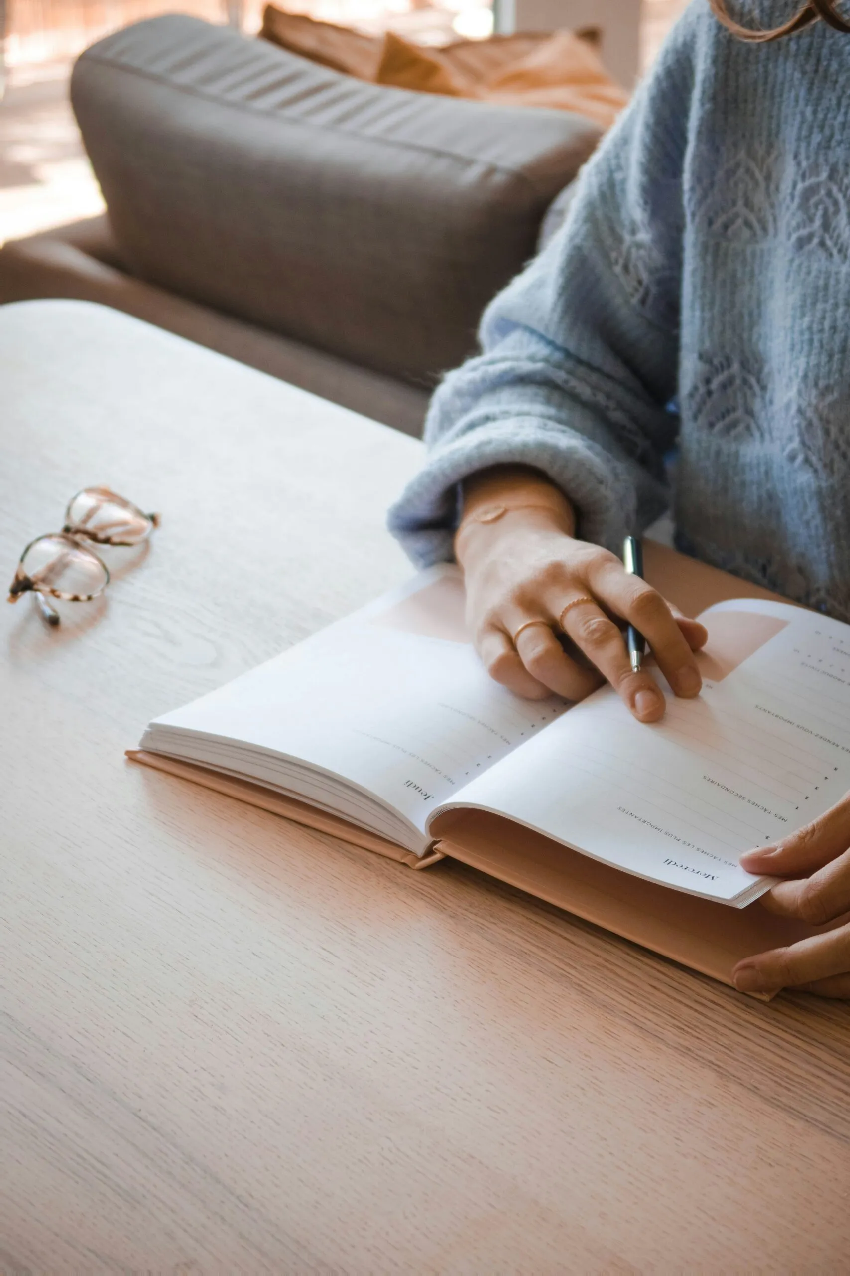 Hand writing in an open notebook beside reading glasses during treatment planning