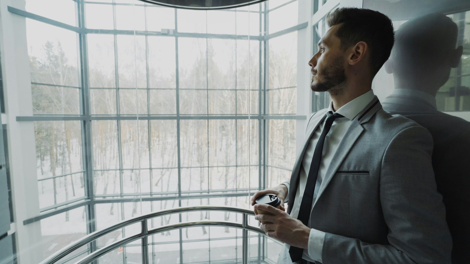 Professional in a suit looking out a large window, representing the executive and professional program
