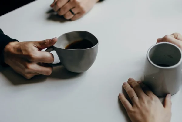 Two people sharing coffee during a supportive one on one conversation, illustrating hemp THC in Texas