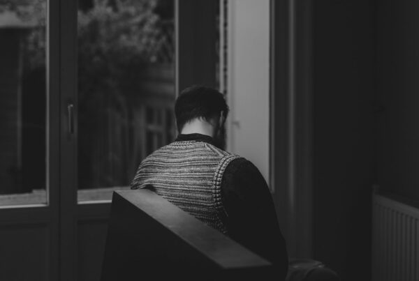Person sitting alone by a window at night, representing the hidden danger of mixing benzos, opioids and alcohol
