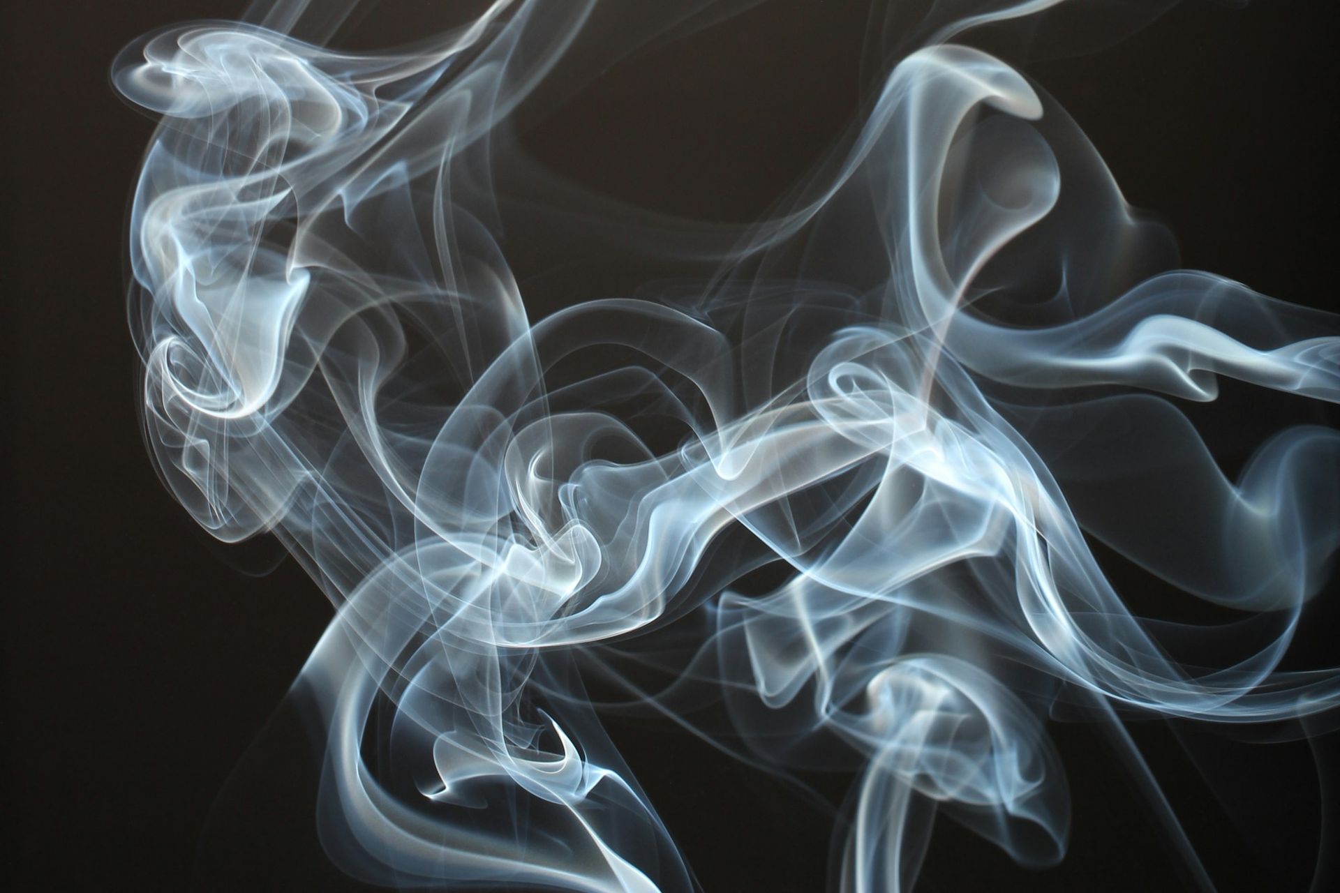 Wisp of vapor drifting against a black background, representing nicotine vaping in recovery