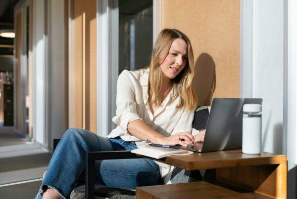 Woman smiling while working on her laptop at home, representing using out of network benefits for treatment