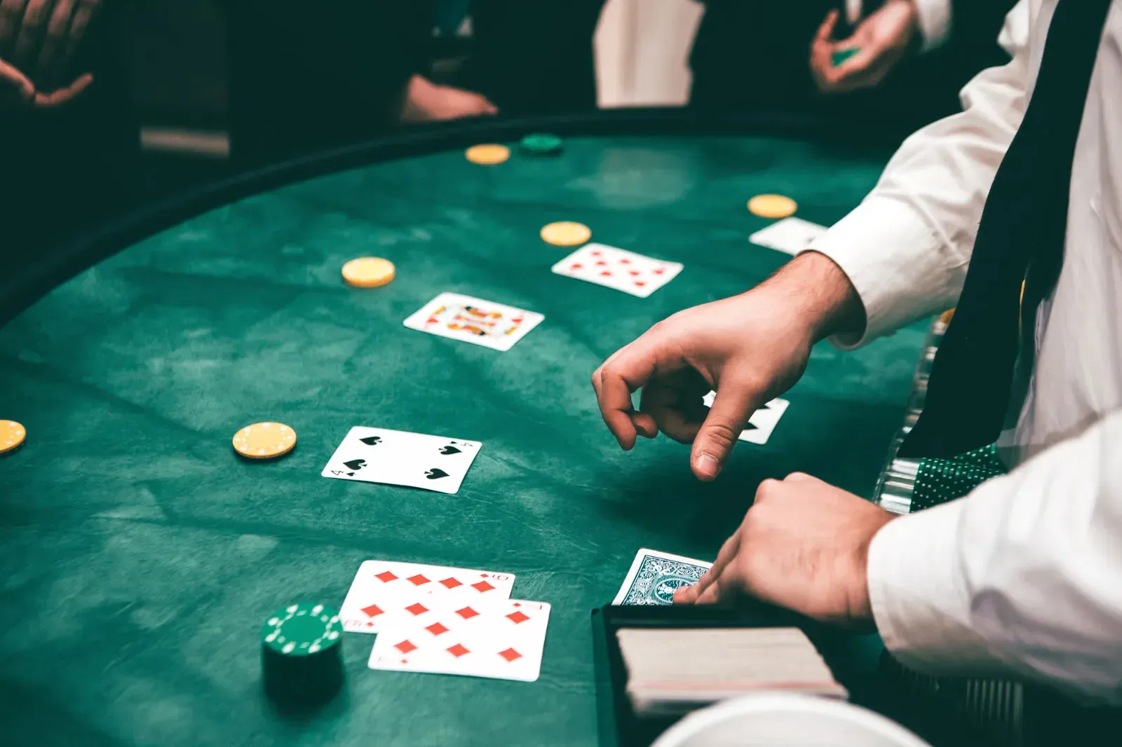 Hands placing a bet with cards and chips at a gaming table, representing gambling addiction, illustrating prediction market gambling