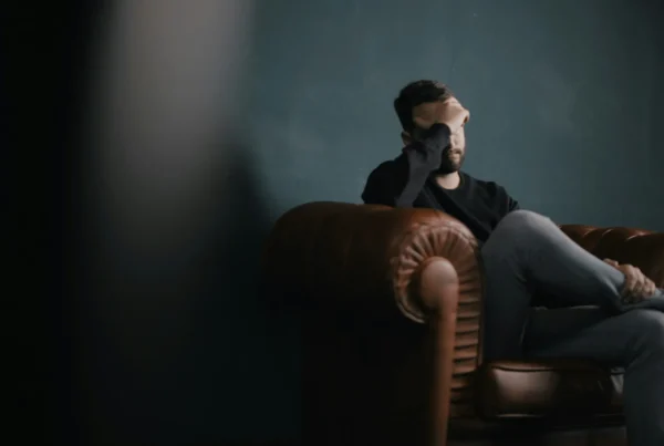Man sitting alone in a dark room with his head lowered, showing depression and isolation, illustrating tianeptine addiction